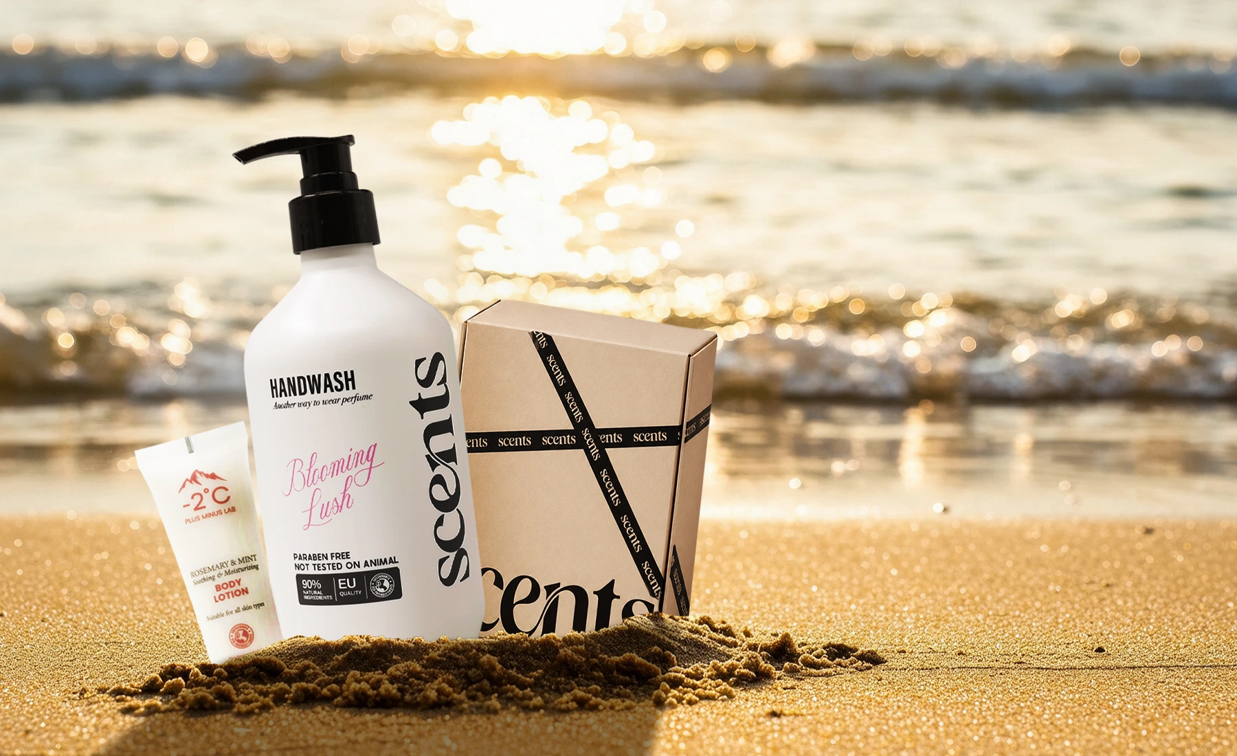 SCENTS Blooming Lush hand wash, a −2°C body lotion tube and a SCENTS gift box standing in sand at sunset