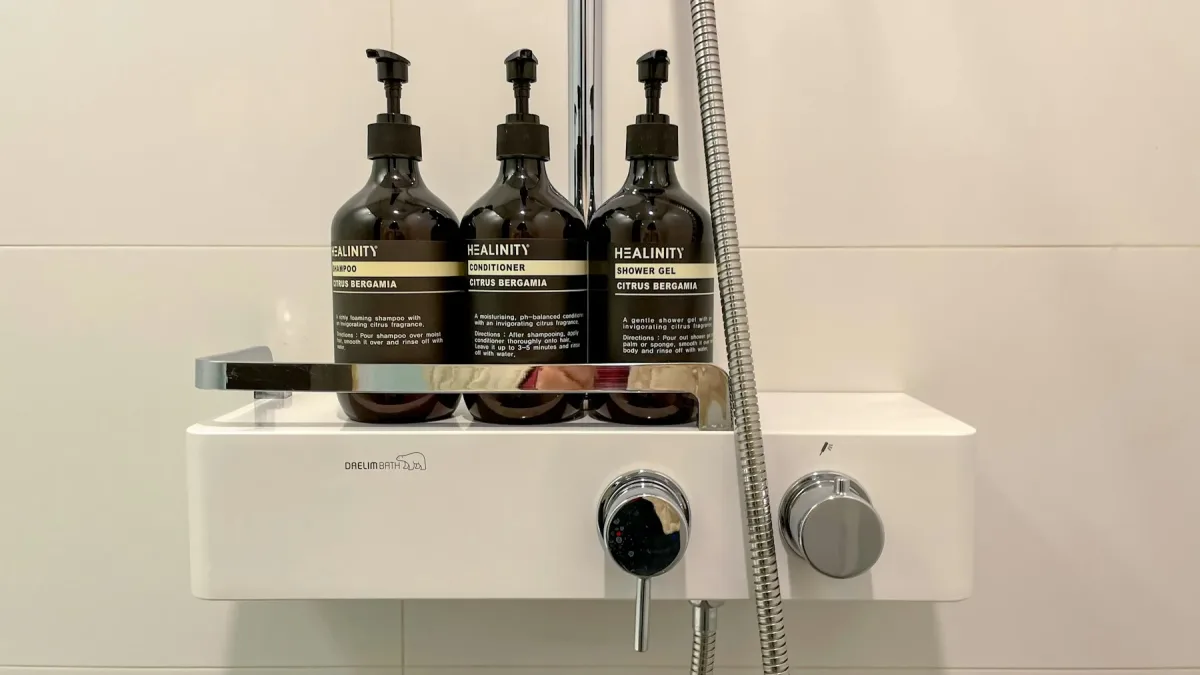 Tiga botol pam bersaiz besar di rak pancuran bilik mandi hotel