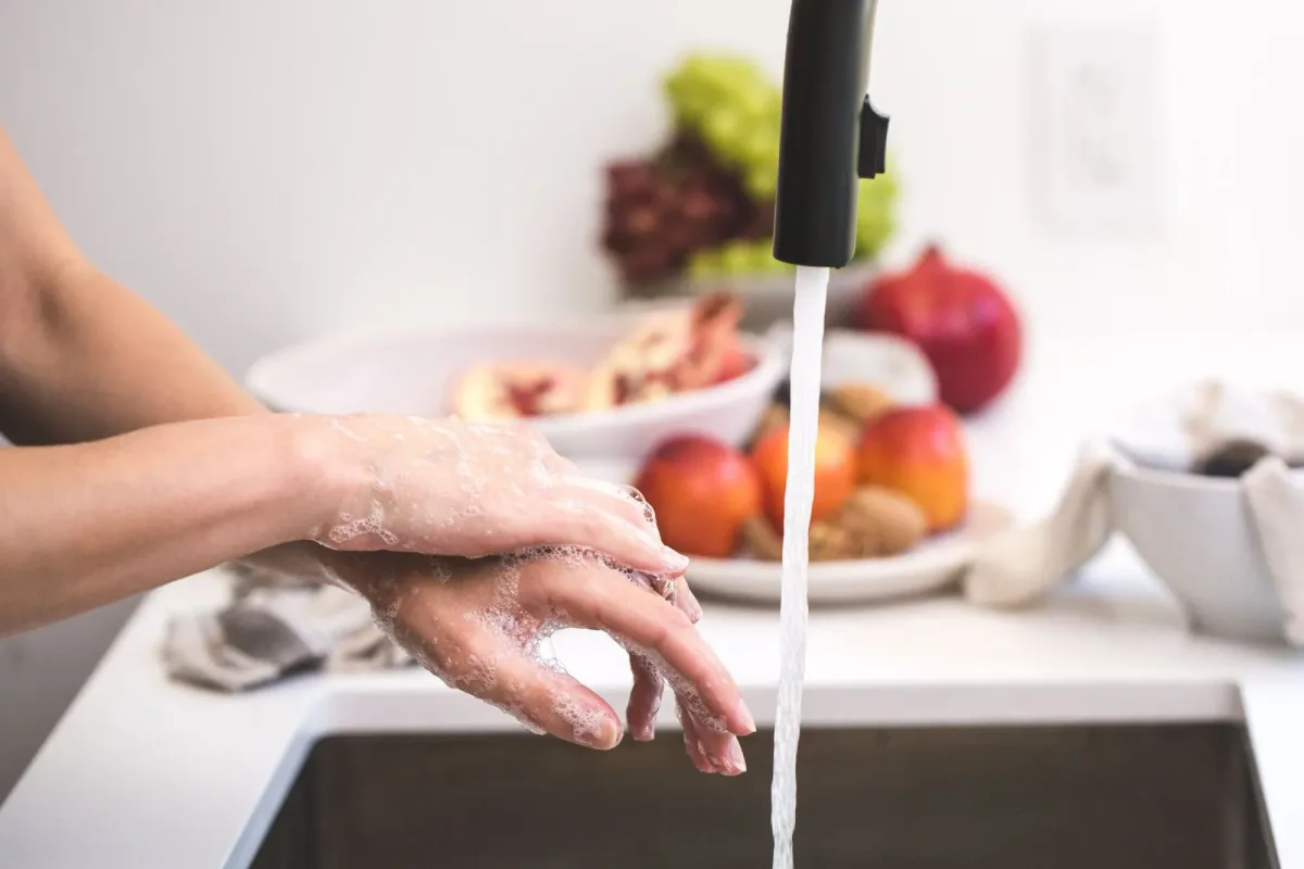 Hands lathered with soap under a running tap